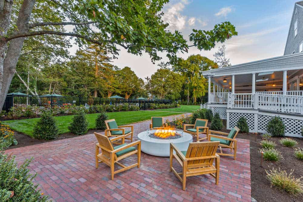 Firepit lounge beside a white porch with chairs arranged for evening gatherings at The Charm on Main