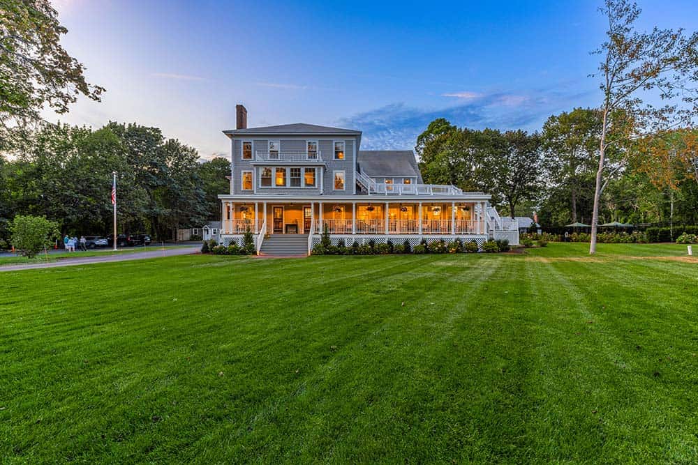 ront lawn of The Manner House with wide green grass and historic home in the background at The Charm on Main in Brewster