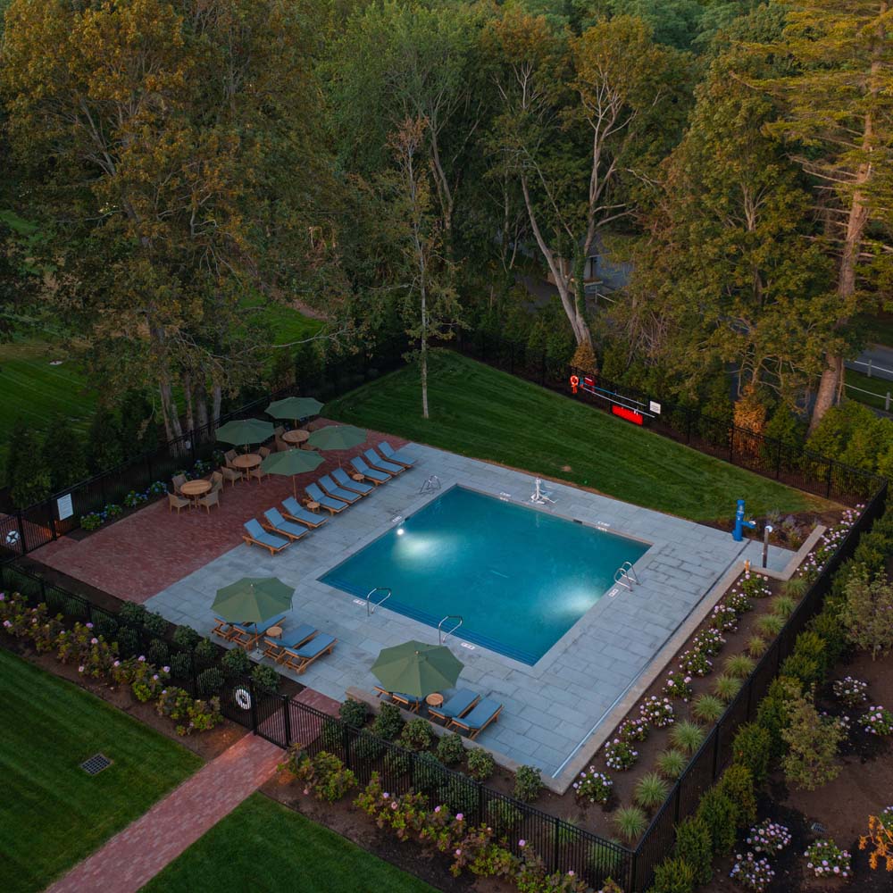Elevated view of outdoor pool with lounge chairs and brick patio at The Charm on Main