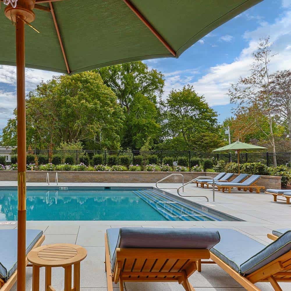 Poolside seating with umbrellas and wooden chairs beside the water at The Charm on Main