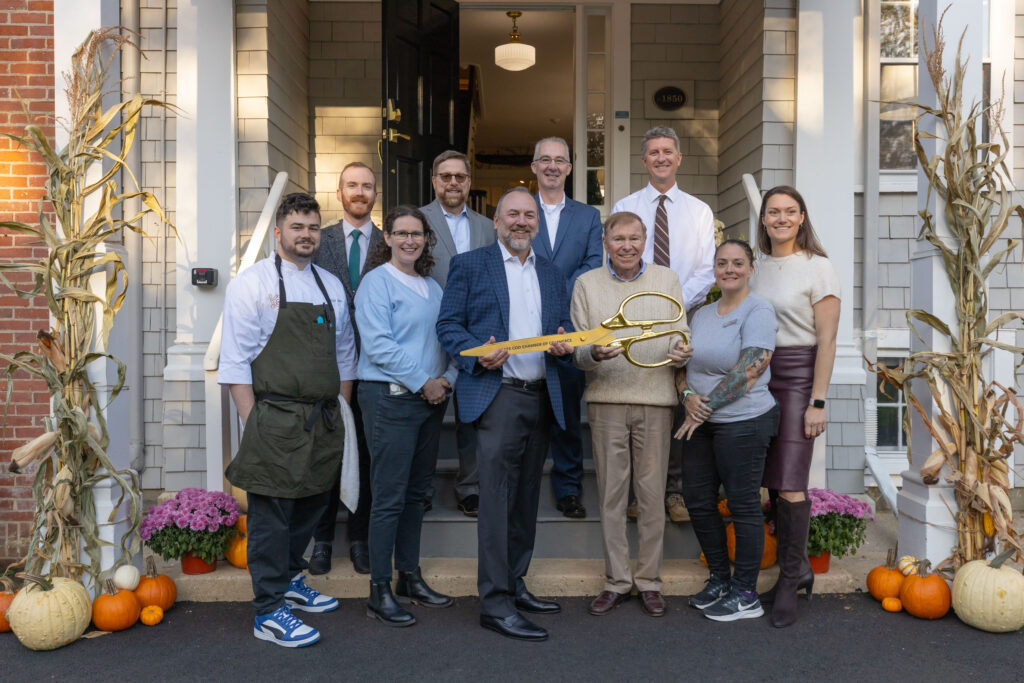 The Corcoran Jennison Hospitality Team at The Charm On Main Ribbon-Cutting Event; A group of ten people standing at the front door of the Inn