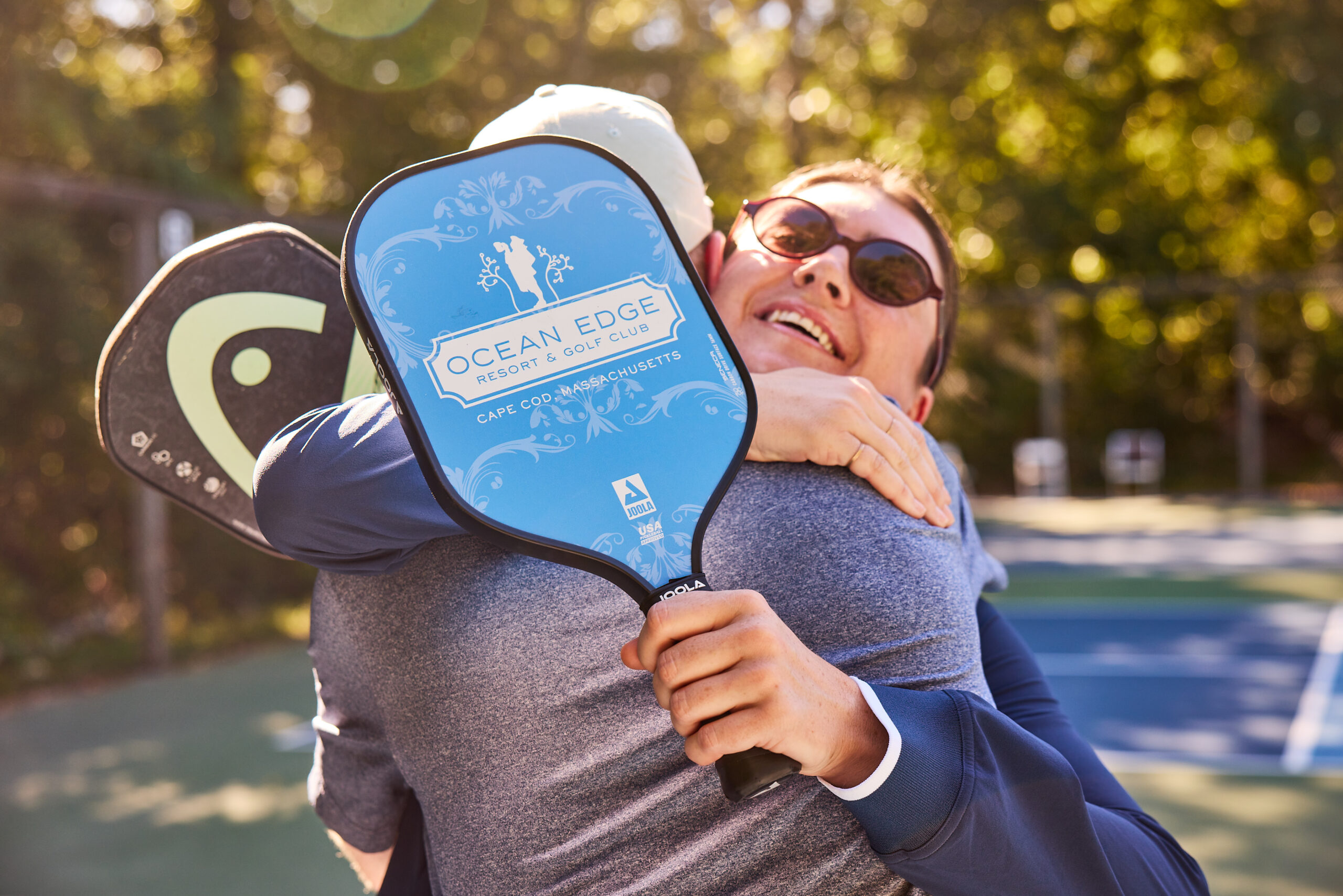 A man and woman hugging on the pickleball court at Ocean Edge